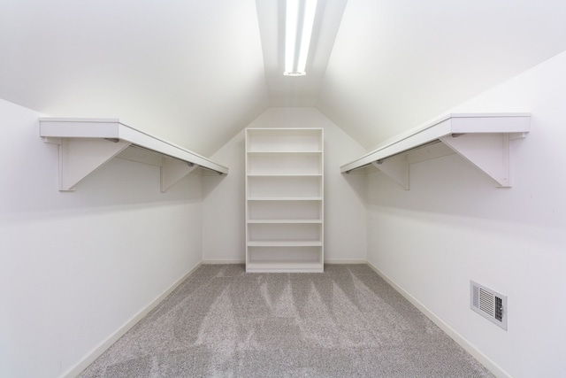 spacious closet featuring light colored carpet and lofted ceiling