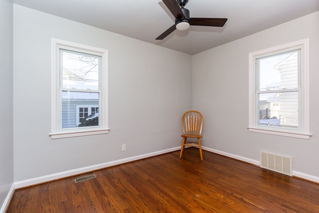 empty room featuring plenty of natural light, dark wood-type flooring, and ceiling fan