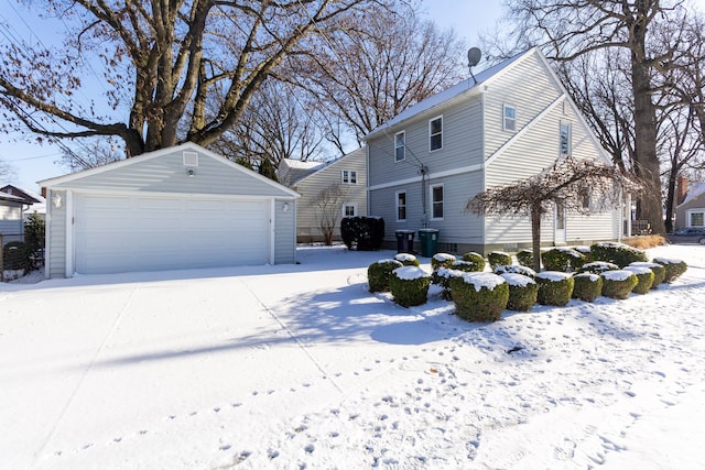 snow covered property with an outbuilding and a garage