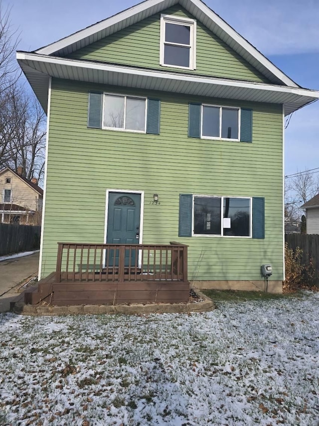 snow covered back of property featuring a deck