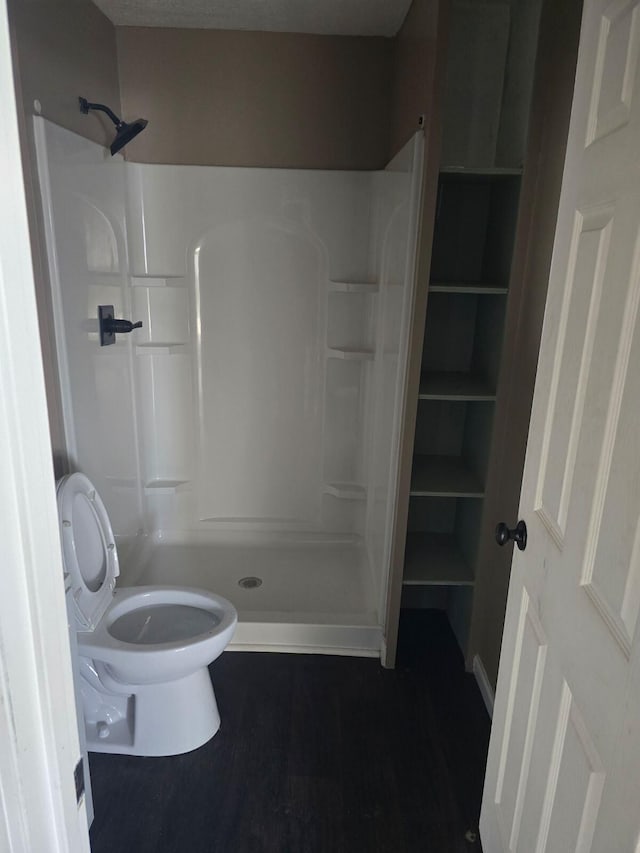 bathroom featuring walk in shower and toilet