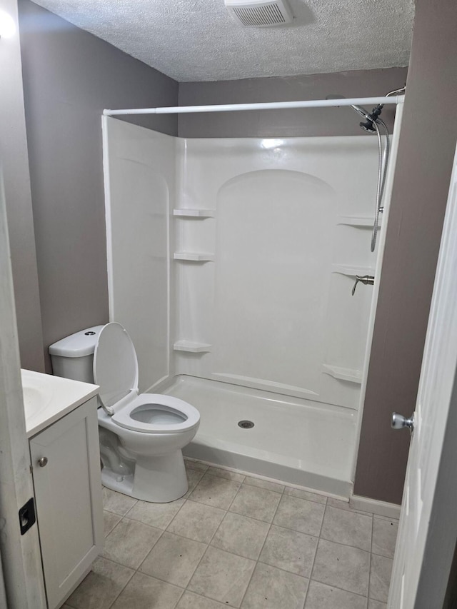 bathroom featuring a textured ceiling, vanity, tile patterned floors, and walk in shower