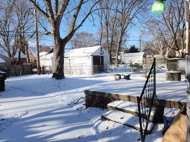 yard layered in snow with a storage unit, an outdoor structure, and fence