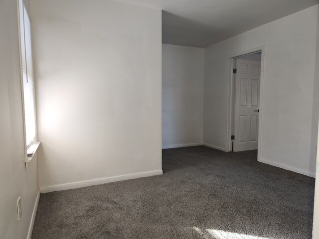 spare room with dark colored carpet