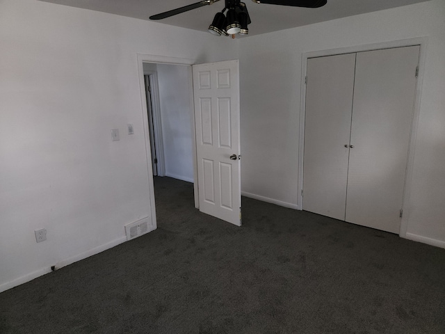 unfurnished bedroom featuring dark colored carpet, a closet, and ceiling fan