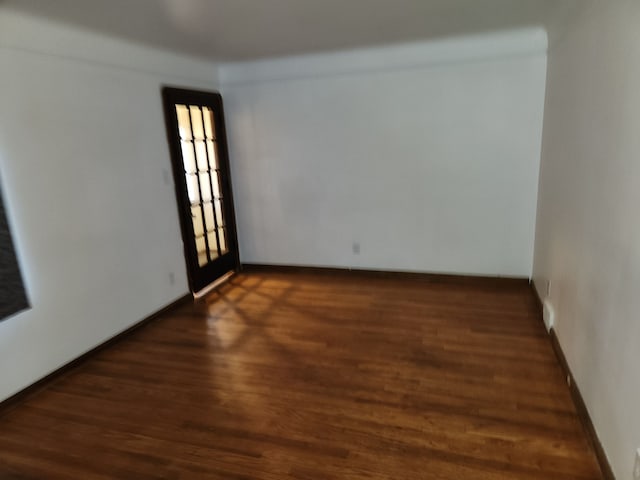 spare room featuring dark wood-type flooring and baseboards