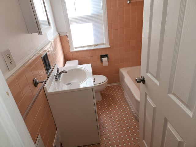 bathroom featuring tile patterned flooring, vanity, toilet, and tile walls