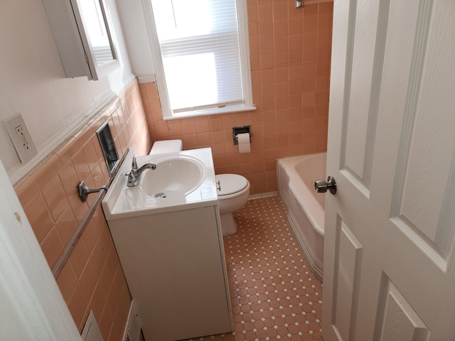 bathroom with toilet, vanity, and tile walls