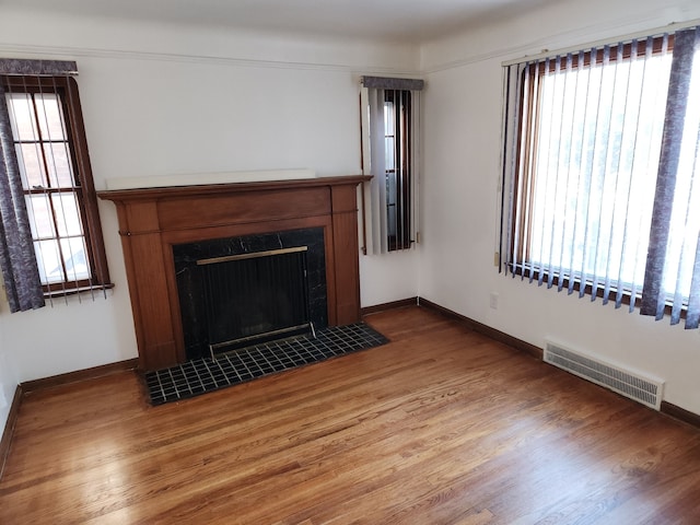 unfurnished living room with visible vents, baseboards, and wood finished floors