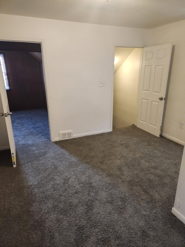 spare room with baseboards, visible vents, and dark carpet