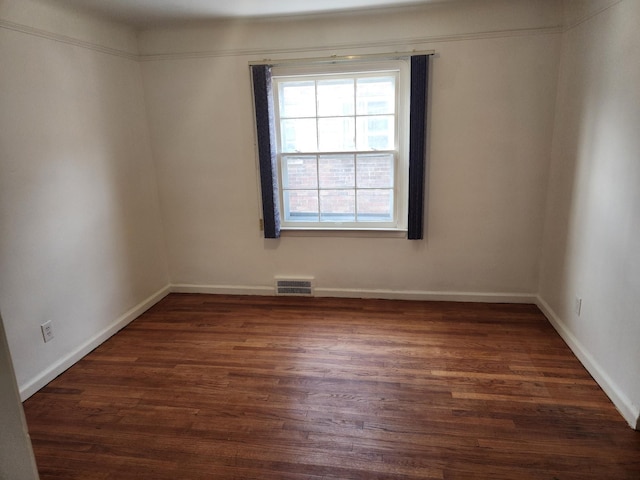 spare room with dark wood-style floors, baseboards, and visible vents