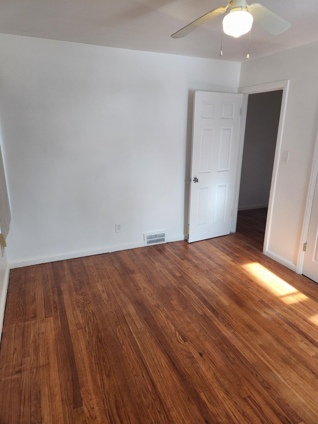 spare room with dark wood-type flooring, visible vents, baseboards, and a ceiling fan