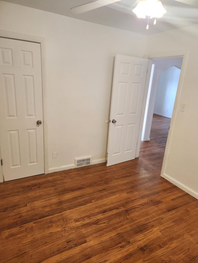 spare room featuring baseboards, ceiling fan, visible vents, and dark wood-style flooring