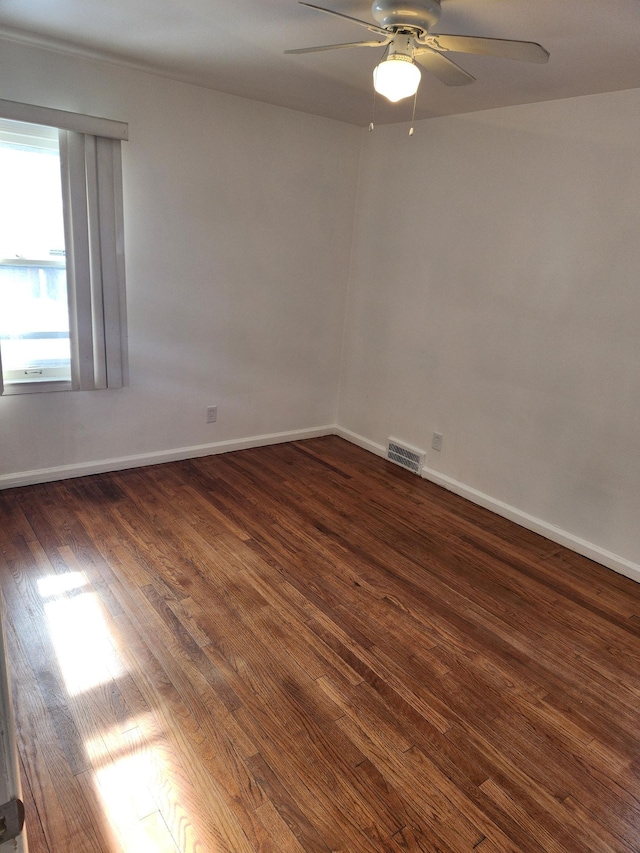 spare room with visible vents, dark wood-style flooring, a ceiling fan, and baseboards