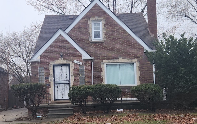 11161 Stockwell St, Detroit, MI 48224 - tudor house featuring a shingled roof, brick siding, and a chimney