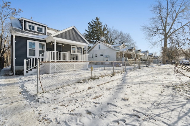 snow covered rear of property featuring covered porch