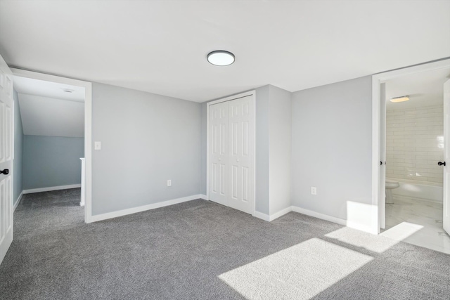 unfurnished bedroom with a closet, carpet floors, and ensuite bath