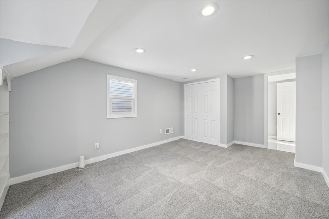 additional living space with light colored carpet and vaulted ceiling