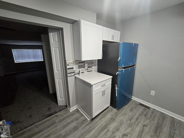 kitchen with light hardwood / wood-style flooring, white cabinets, and fridge