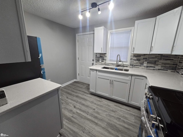 kitchen featuring sink, black / electric stove, a textured ceiling, white cabinets, and light wood-type flooring