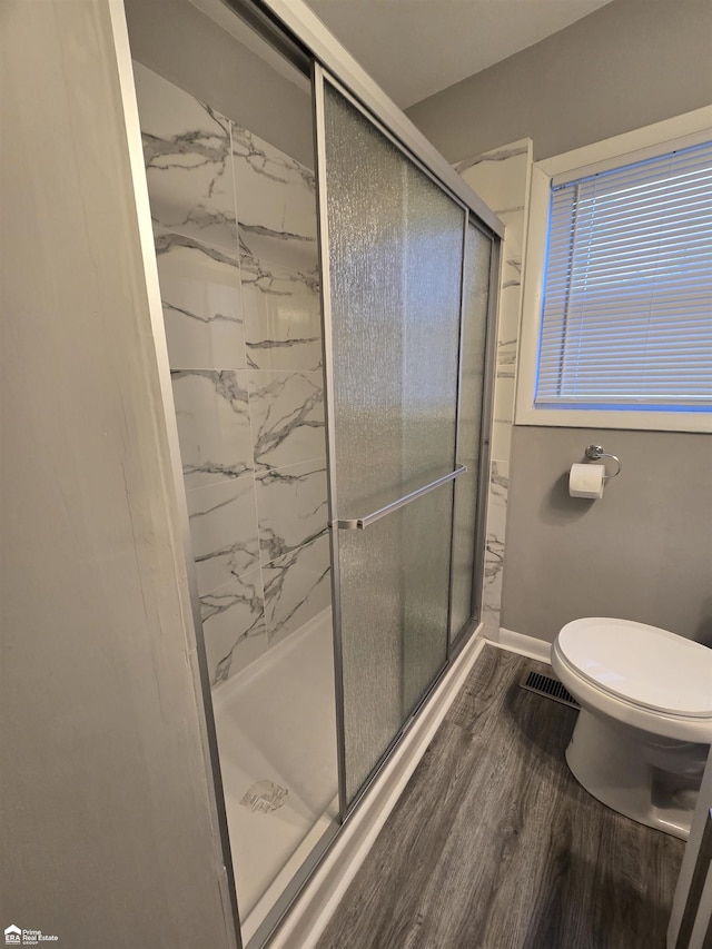 bathroom featuring hardwood / wood-style floors, toilet, and walk in shower