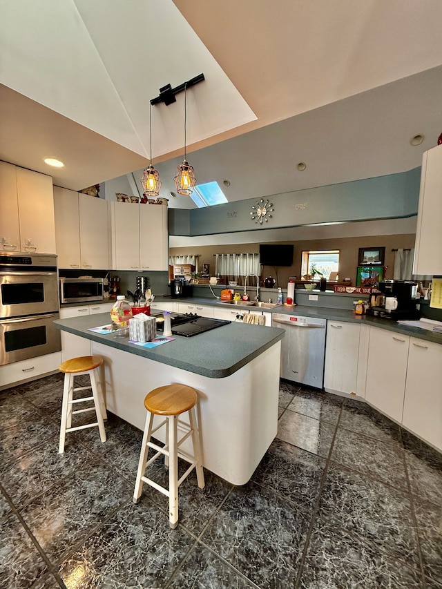 kitchen featuring appliances with stainless steel finishes, a breakfast bar area, dark countertops, and a center island