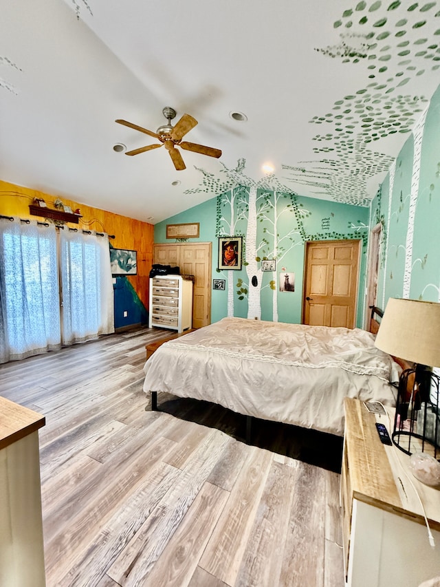 bedroom featuring lofted ceiling, light hardwood / wood-style flooring, and wooden walls