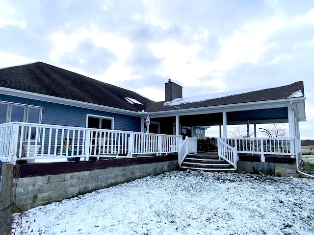 snow covered house featuring a shingled roof and a chimney