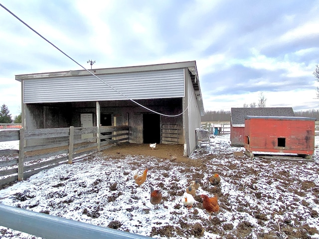 snow covered structure with an outbuilding and an exterior structure