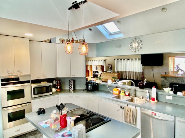 kitchen featuring lofted ceiling with skylight, appliances with stainless steel finishes, pendant lighting, white cabinetry, and sink