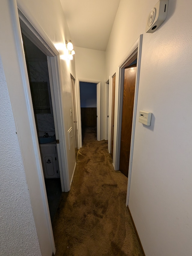 corridor with dark carpet and sink