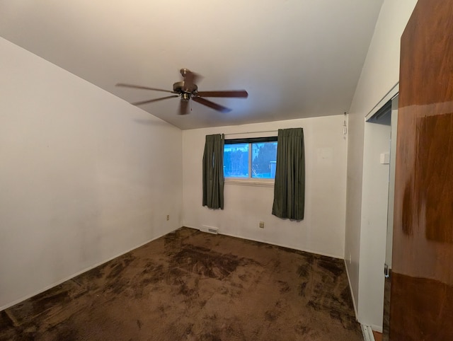 empty room with ceiling fan and dark carpet