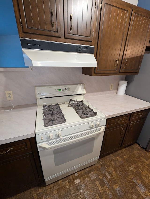 kitchen featuring dark brown cabinetry, stainless steel fridge, and white gas range oven