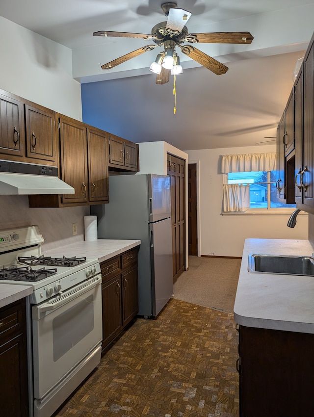 kitchen featuring sink, white gas range oven, ceiling fan, stainless steel fridge, and dark brown cabinets