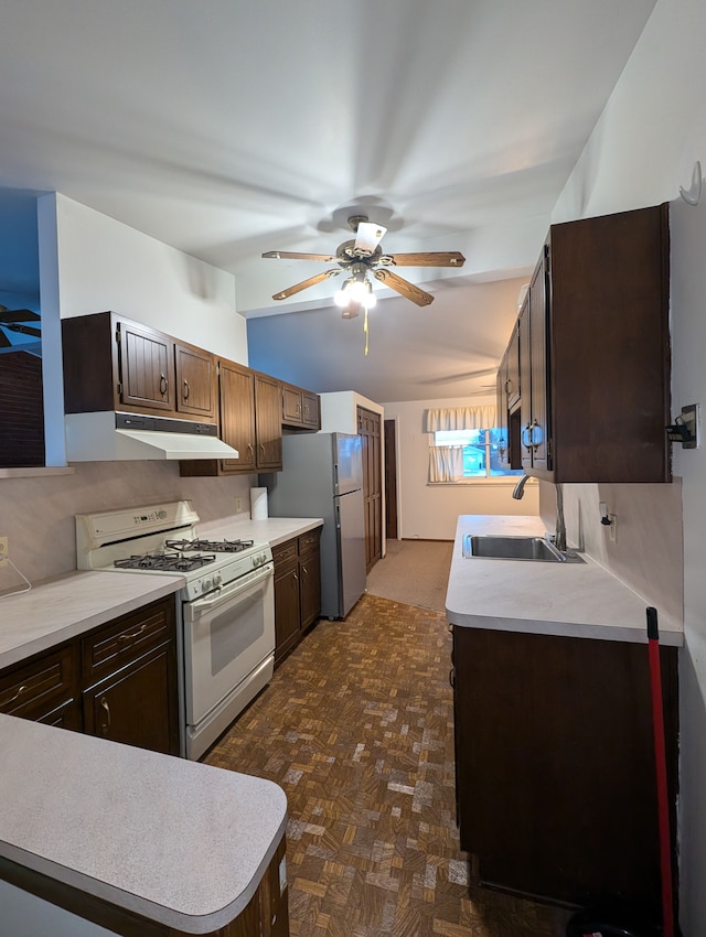 kitchen with stainless steel refrigerator, ceiling fan, white gas stove, sink, and dark brown cabinets