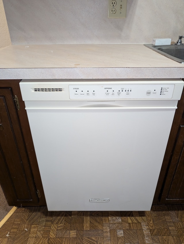 interior details with dark parquet flooring, dark brown cabinetry, and white dishwasher