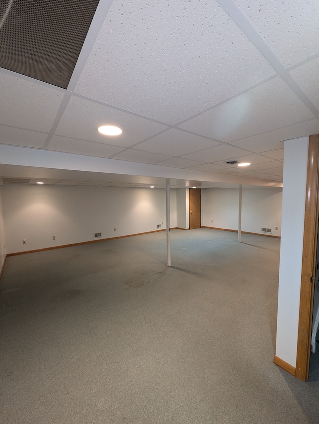 basement with a paneled ceiling and carpet floors