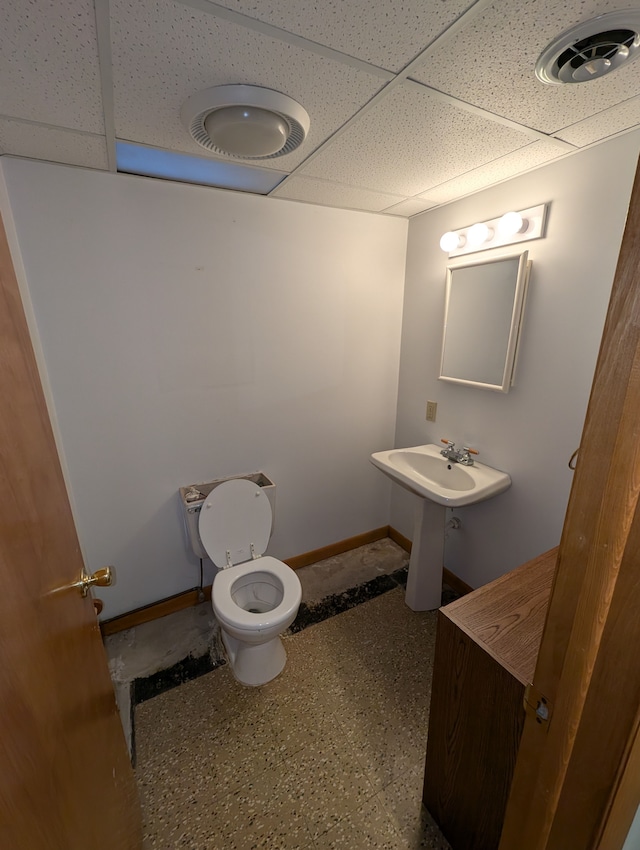 bathroom with toilet and a drop ceiling