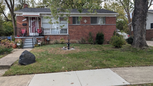 view of front facade with brick siding, a chimney, and a front yard