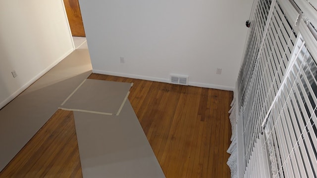 empty room featuring visible vents, baseboards, and wood finished floors