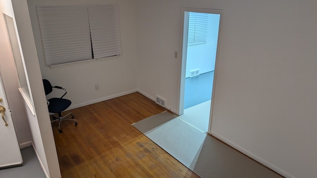 office space featuring wood finished floors, visible vents, and baseboards