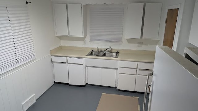 kitchen with visible vents, a sink, concrete floors, white cabinets, and light countertops