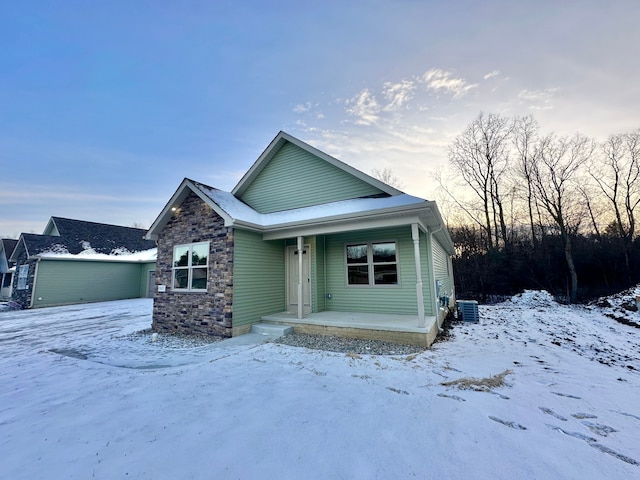 view of front of house featuring covered porch, stone siding, and central AC unit