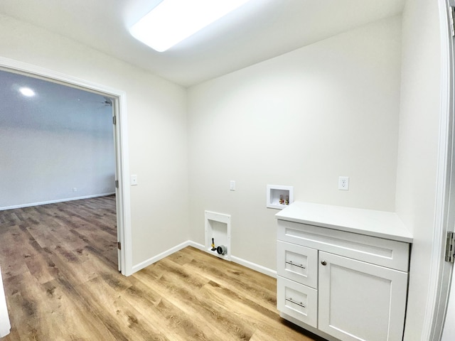 washroom featuring hookup for a washing machine, cabinet space, baseboards, and light wood-style floors