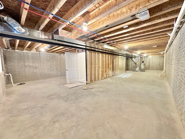 unfinished basement with heating unit, brick wall, and gas water heater