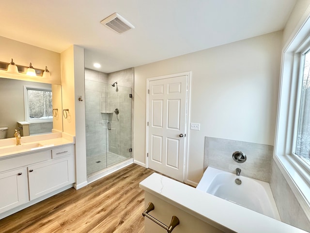 bathroom with a stall shower, plenty of natural light, wood finished floors, and visible vents