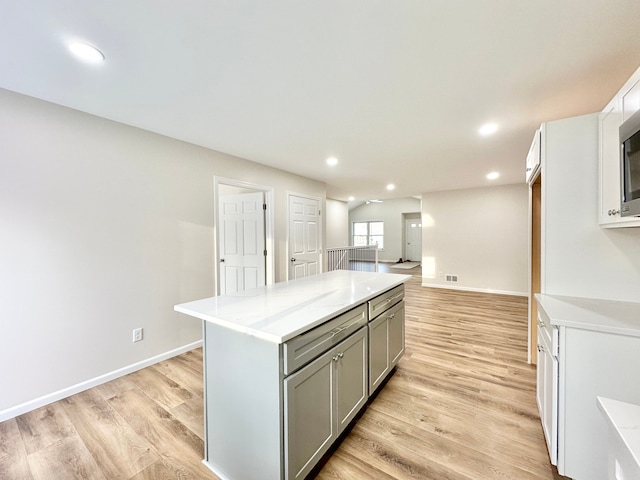 kitchen with recessed lighting, light wood-style flooring, a kitchen island, and gray cabinetry