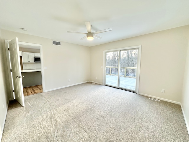 empty room featuring light colored carpet, visible vents, and baseboards