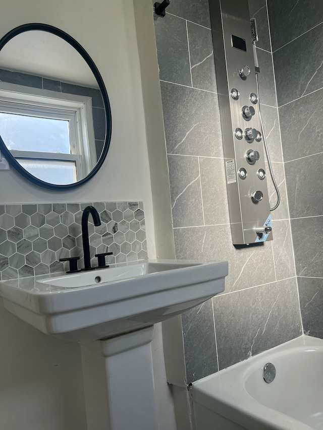 bathroom featuring tiled shower / bath, backsplash, and tile walls