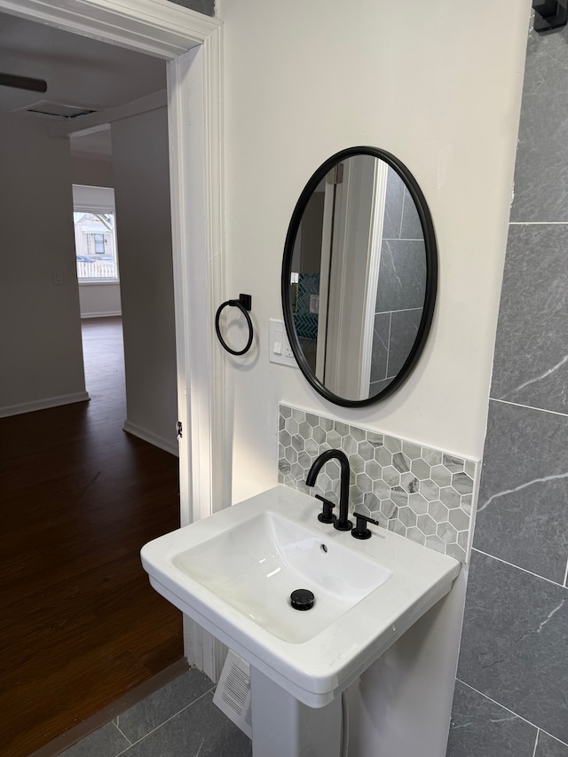 bathroom with sink, hardwood / wood-style flooring, tasteful backsplash, and tile walls